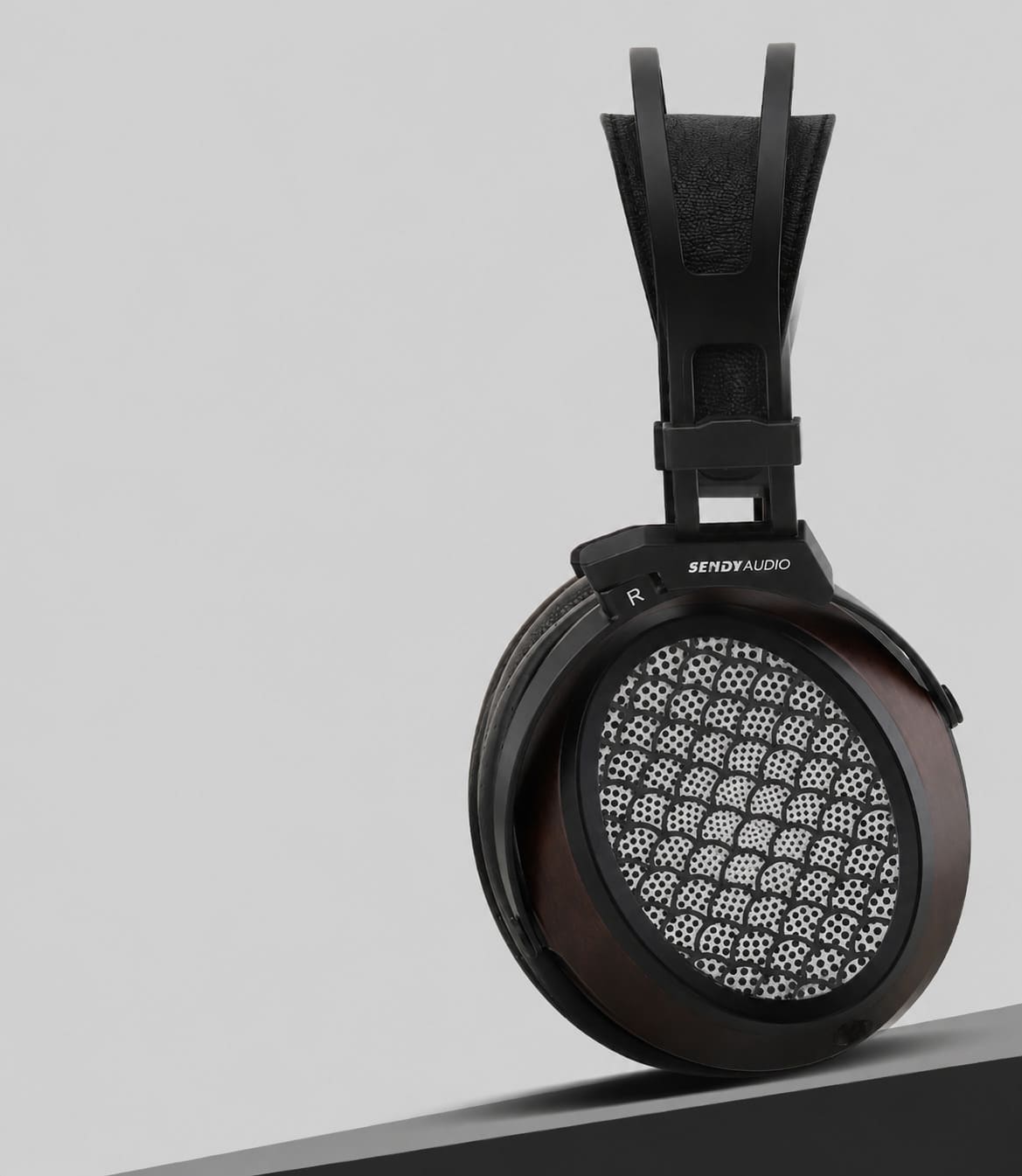 Cupa dreaptă a căștilor Sendy Audio AIVA 2 văzută din lateral, cu carcasă din lemn natural, furcă metalică și grilaj cu model de solzi