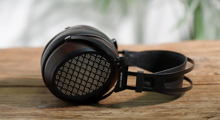 Sendy Audio AIVA 2 pe o masă de lemn, vedere laterală cu cupă deschisă și bandă de susținere pentru cap vizibile