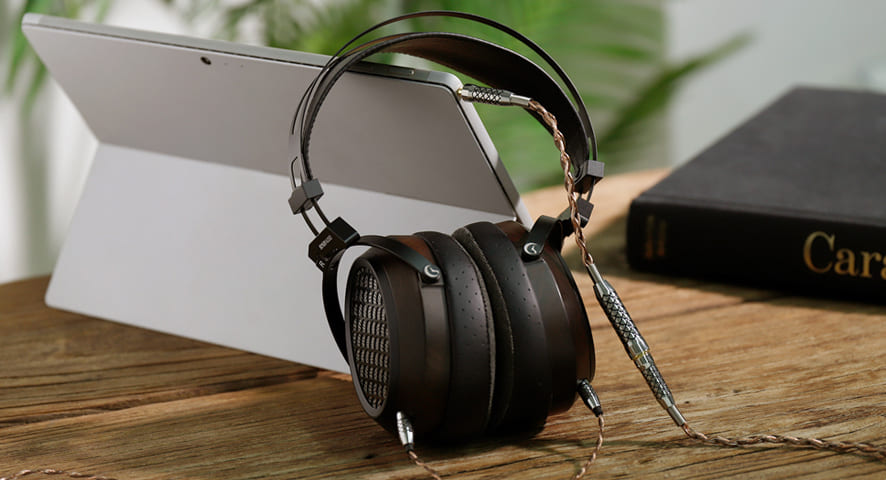 Sendy Audio AIVA 2 conectate la o tabletă, pe o masă de lemn, cu cablul și adaptorul din pachet